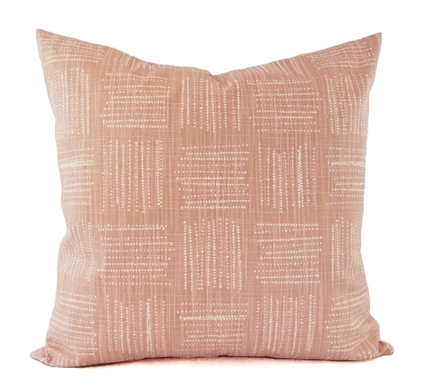 A blush pink pillow with a white geometric dot pattern.