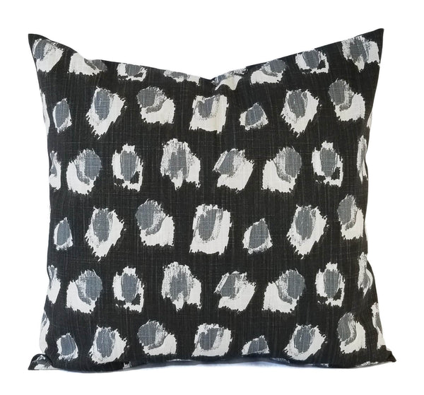 A black pillow cover with a grey abstract dot pattern.