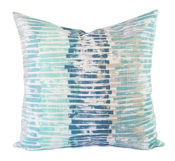 A blue, grey, white, and teal pillow in a horizontal striped print.