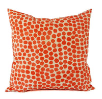 A cream pillow cover with orange polka dots.