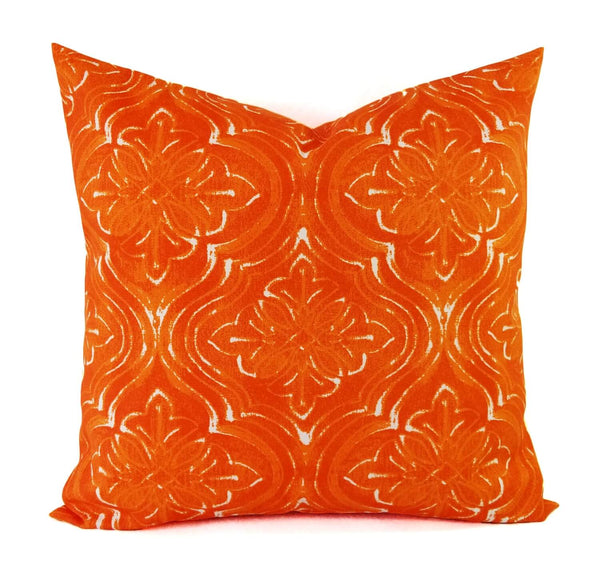 An orange and white damask pillow.