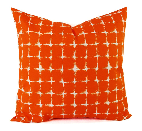 A bright orange pillow with a boxed geometric print.