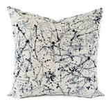 A blue and soft grey pillow in an art splatter print.