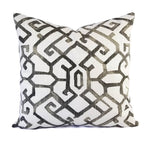 A pillow with a white background and a taupe grey geometric print.