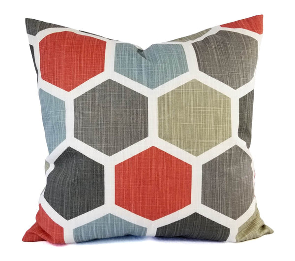 A pillow with a red, grey, and soft blue hexagon pattern.